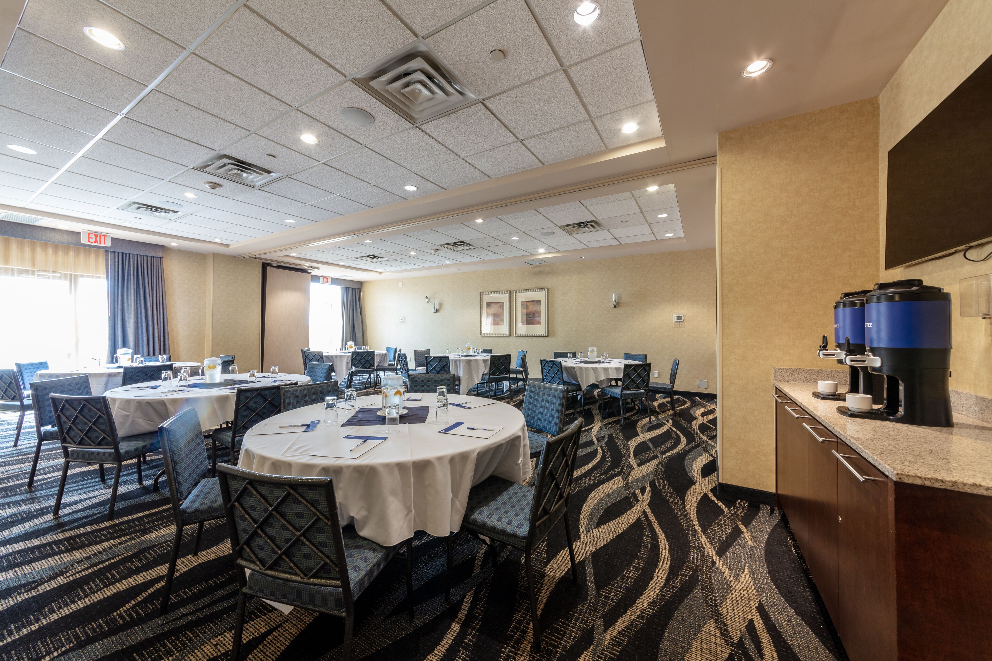 A conference room with round tables, chairs, and a coffee station.