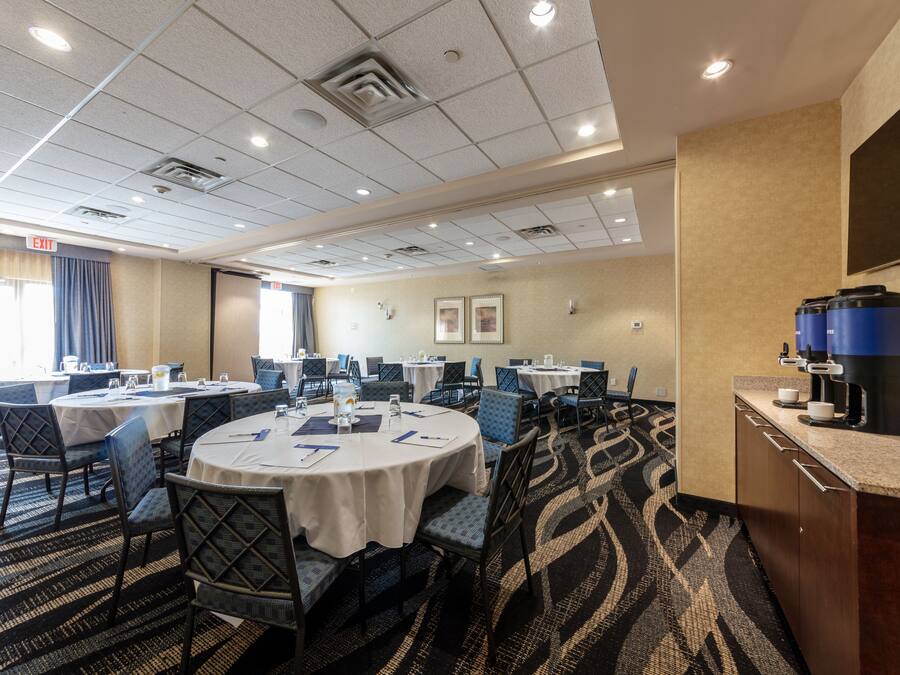 A conference room with round tables, chairs, and a coffee station.