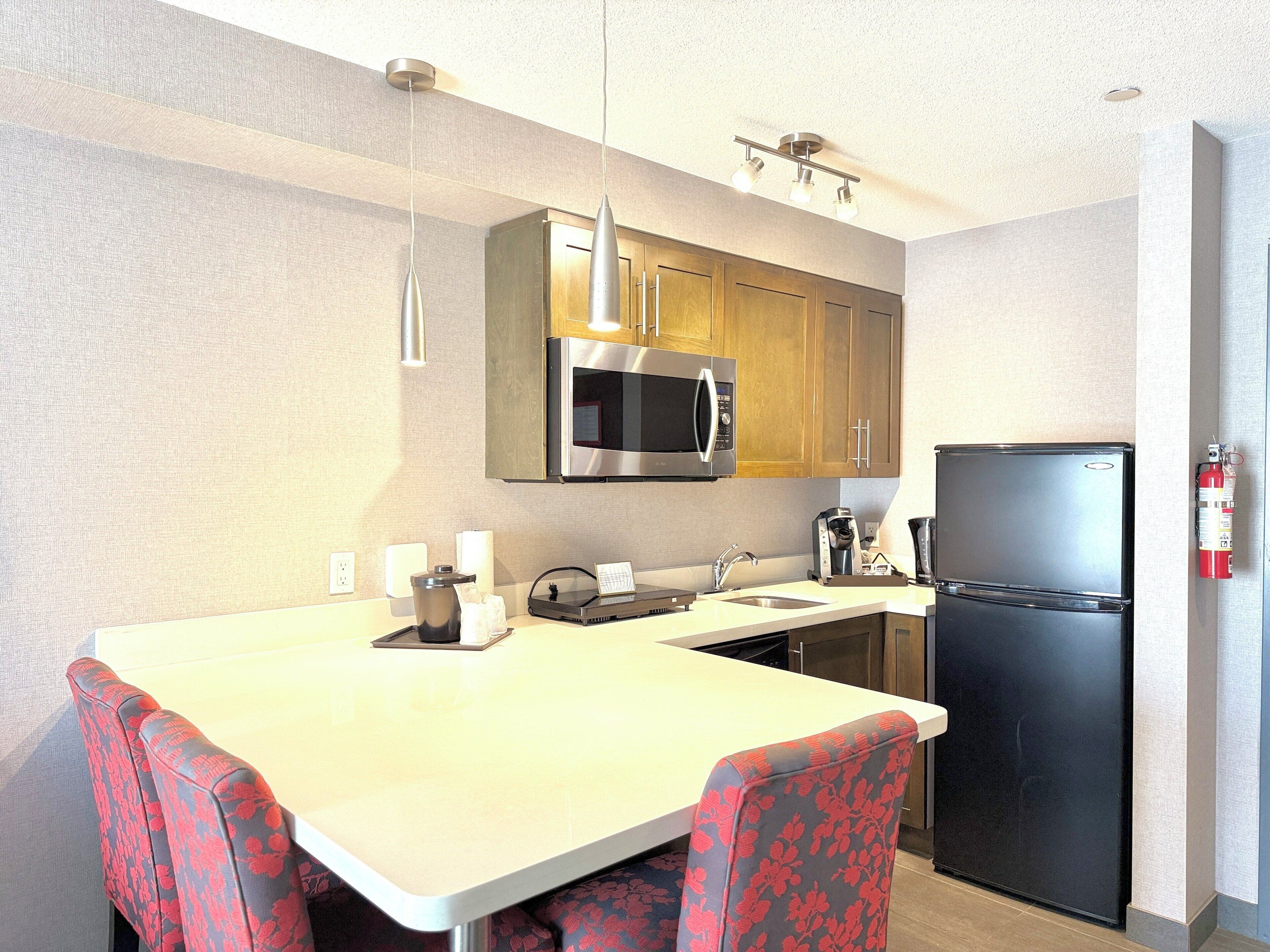 A compact kitchen with a microwave, coffee maker, and refrigerator.