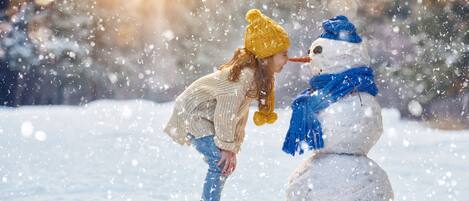 A person interacting with a snowman in a snowy outdoor setting.
