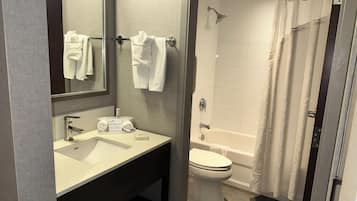 Un baño moderno con lavamanos, espejo, toallero, inodoro y zona de ducha.