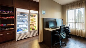 A hotel room with a desk, two chairs, a refrigerator stocked with beverages, and a 'No Food or Drink' sign. - Holiday Inn Express Hotel & Suites Riverport Richmond by IHG (Richmond)