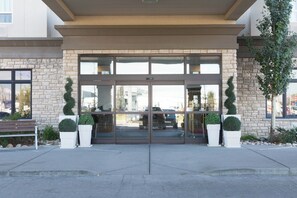 A building entrance with a glass door, stone walls, and potted plants. - Holiday Inn Hotel & Suites West Edmonton by IHG (Edmonton)