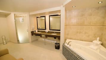 Un baño de hotel con tocador de doble lavabo, una bañera grande y una zona de ducha separada.