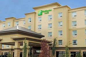 Un hotel Holiday Inn & Suites con fachada plana, múltiples ventanas y un acceso cubierto.