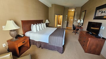 Une chambre d’hôtel avec un grand lit, un bureau avec une télévision, une chaise et une lampe.