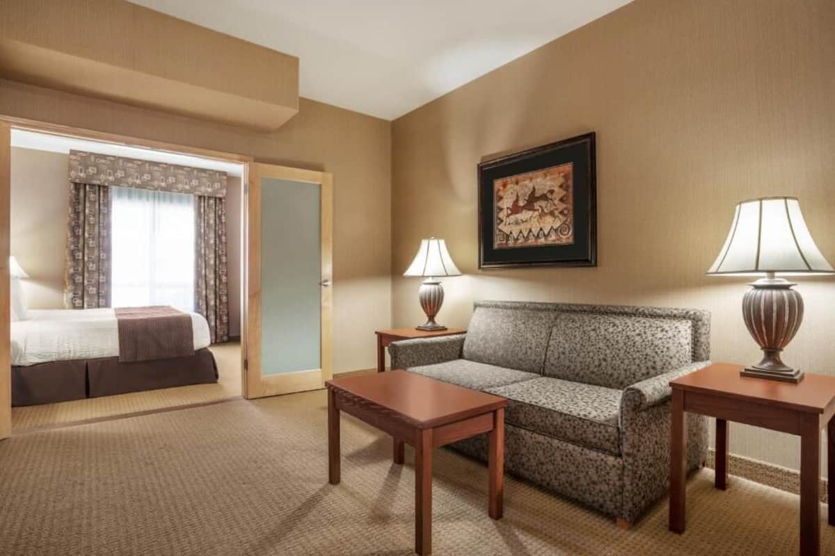 Une chambre d’hôtel avec un lit, un canapé, deux tables de chevet et un tableau encadré au mur.