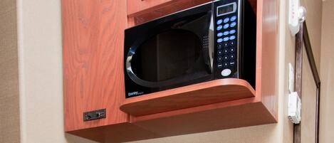 A compact kitchenette with a microwave, coffee maker, and dishwasher.