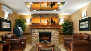 A lobby with leather sofas, a fireplace, a stone wall, and artwork. - Days Inn & Suites by Wyndham Strathmore (Strathmore)