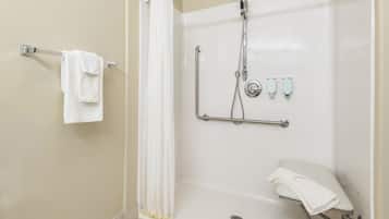 A modern shower area with a grab bar, a white towel, and a handheld showerhead.