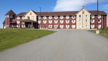 Un grande hotel su più piani, con un ingresso centrale, numerose finestre e un parcheggio.