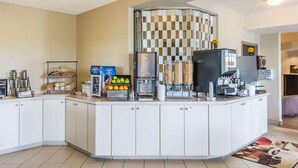 Un bufé de desayuno con máquina de café, estación de té y diversas opciones de alimentos.