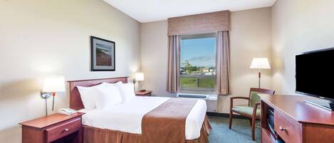 Habitación de hotel con cama, escritorio, silla, televisión y ventana con vistas.