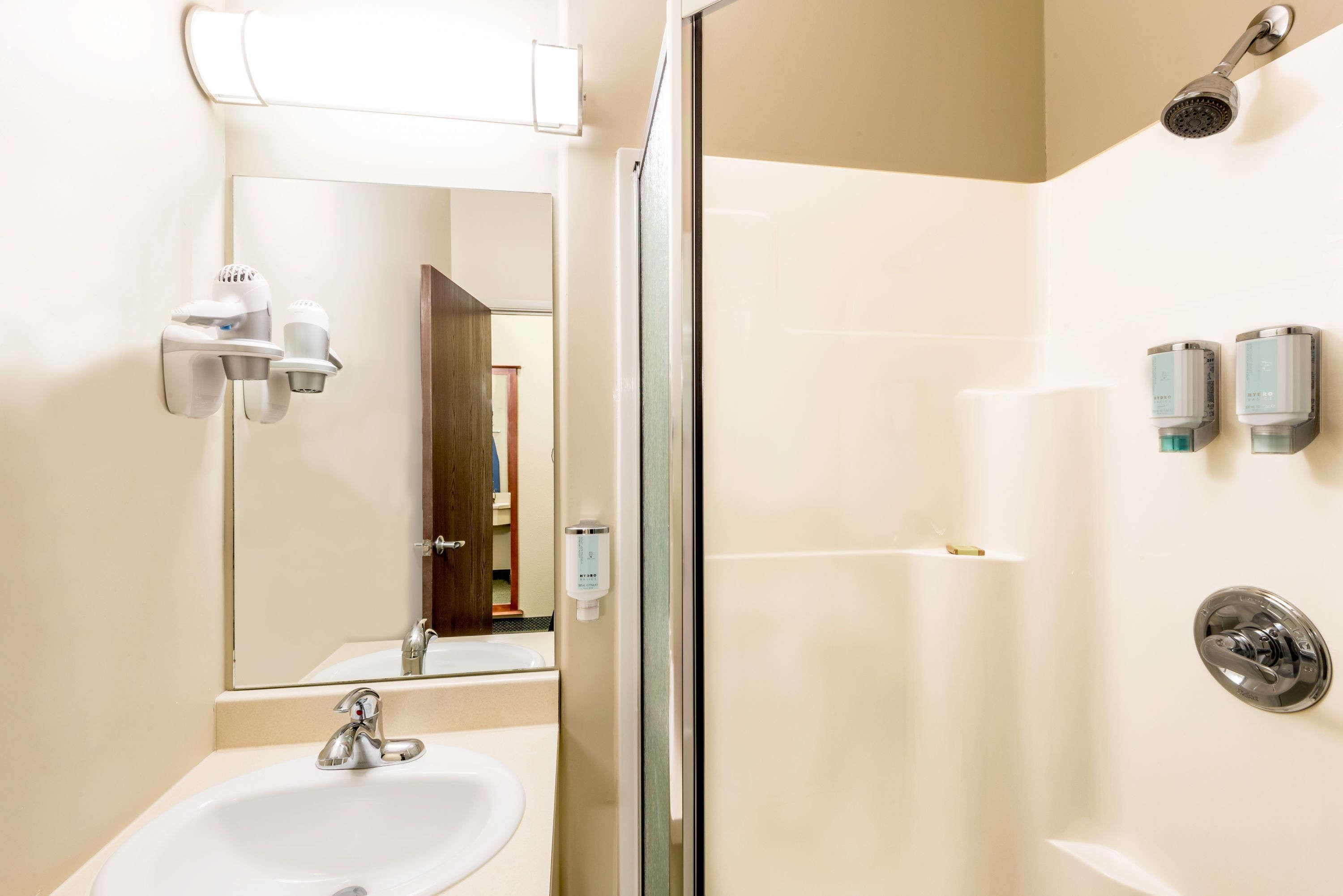 A modern bathroom with a sink, mirror, and shower.