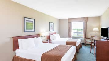 A hotel room with two beds, a desk, a chair, and a television.