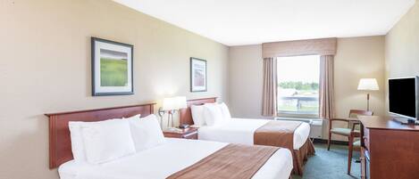 A hotel room with two beds, a desk, a chair, and a television.