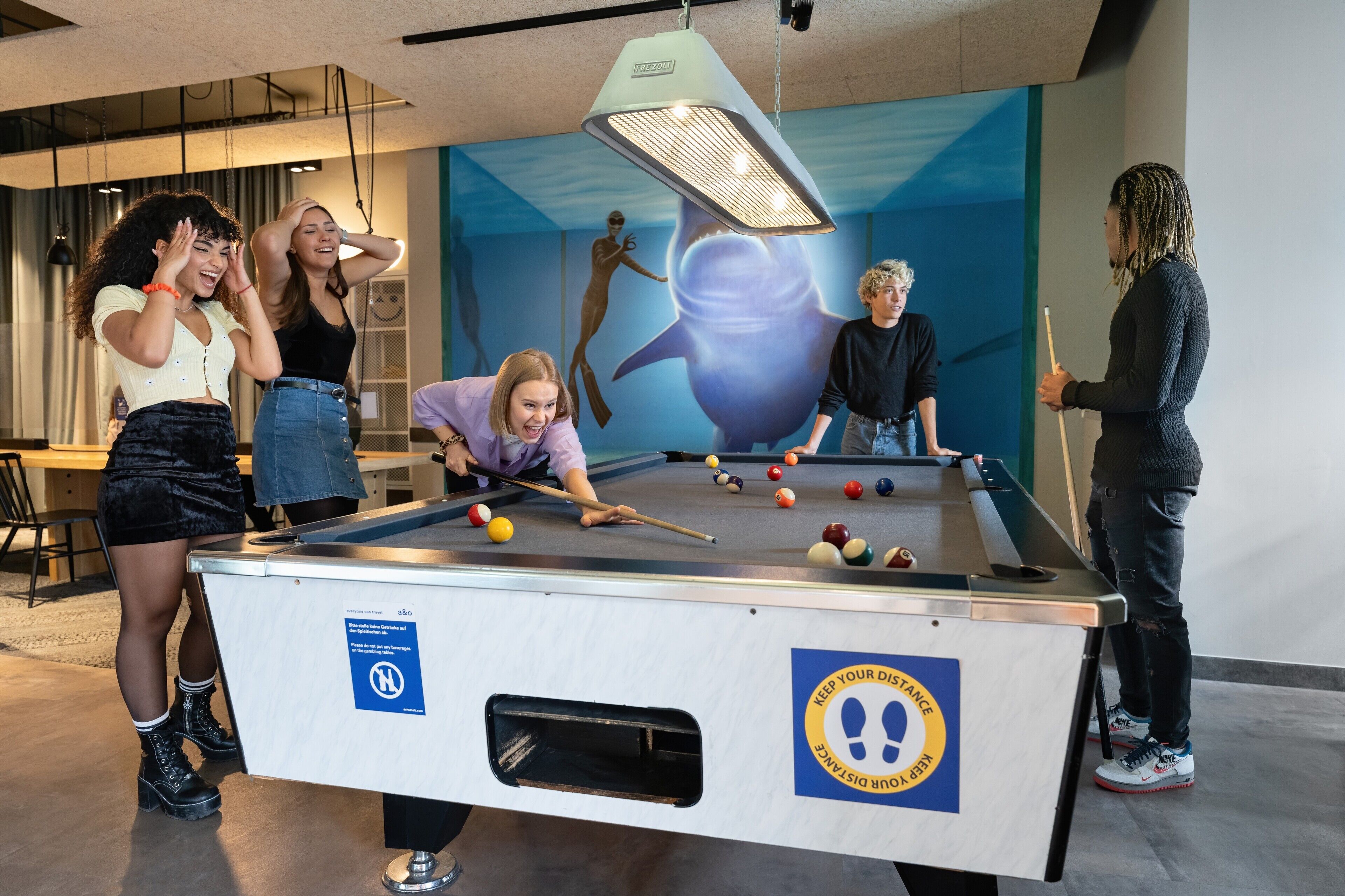 A pool table in a room with a mural of a diver and a shark.