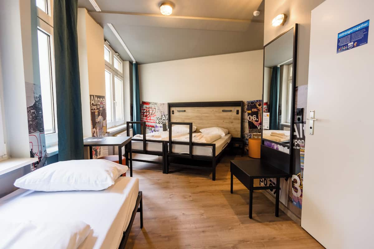 Ein Hotelzimmer mit Bett, Schreibtisch, Stuhl, Spiegel und Fenster.