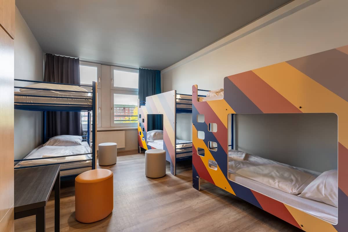 Ein Schlafsaalzimmer mit Etagenbetten, einem kleinen Tisch und einem Fenster.