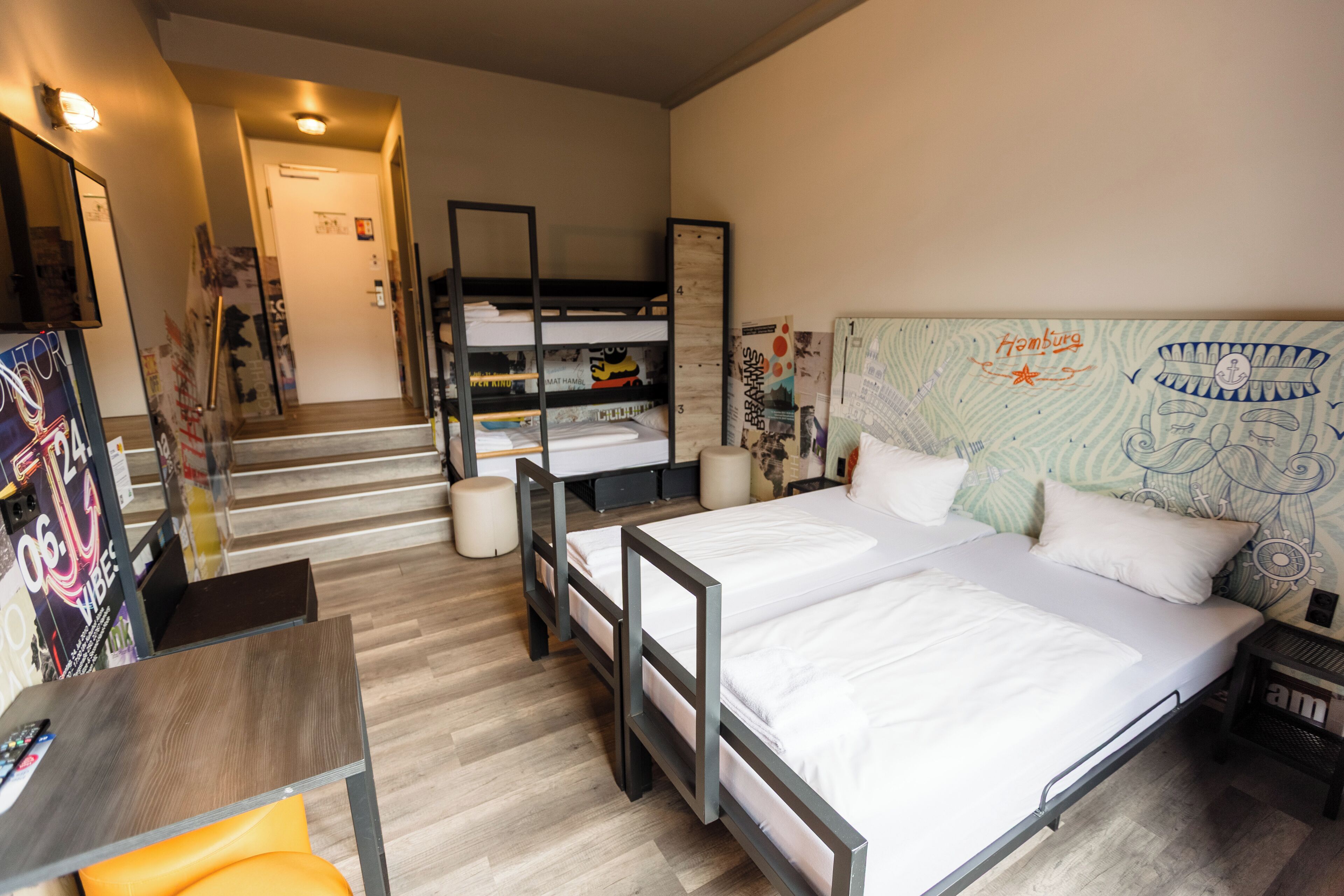 Una habitación de hotel compacta con una cama litera, un escritorio y una pequeña mesa.