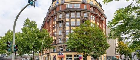 Un edificio de varios pisos con una esquina redondeada, que presenta un llamativo letrero 'a&o' en la planta baja.