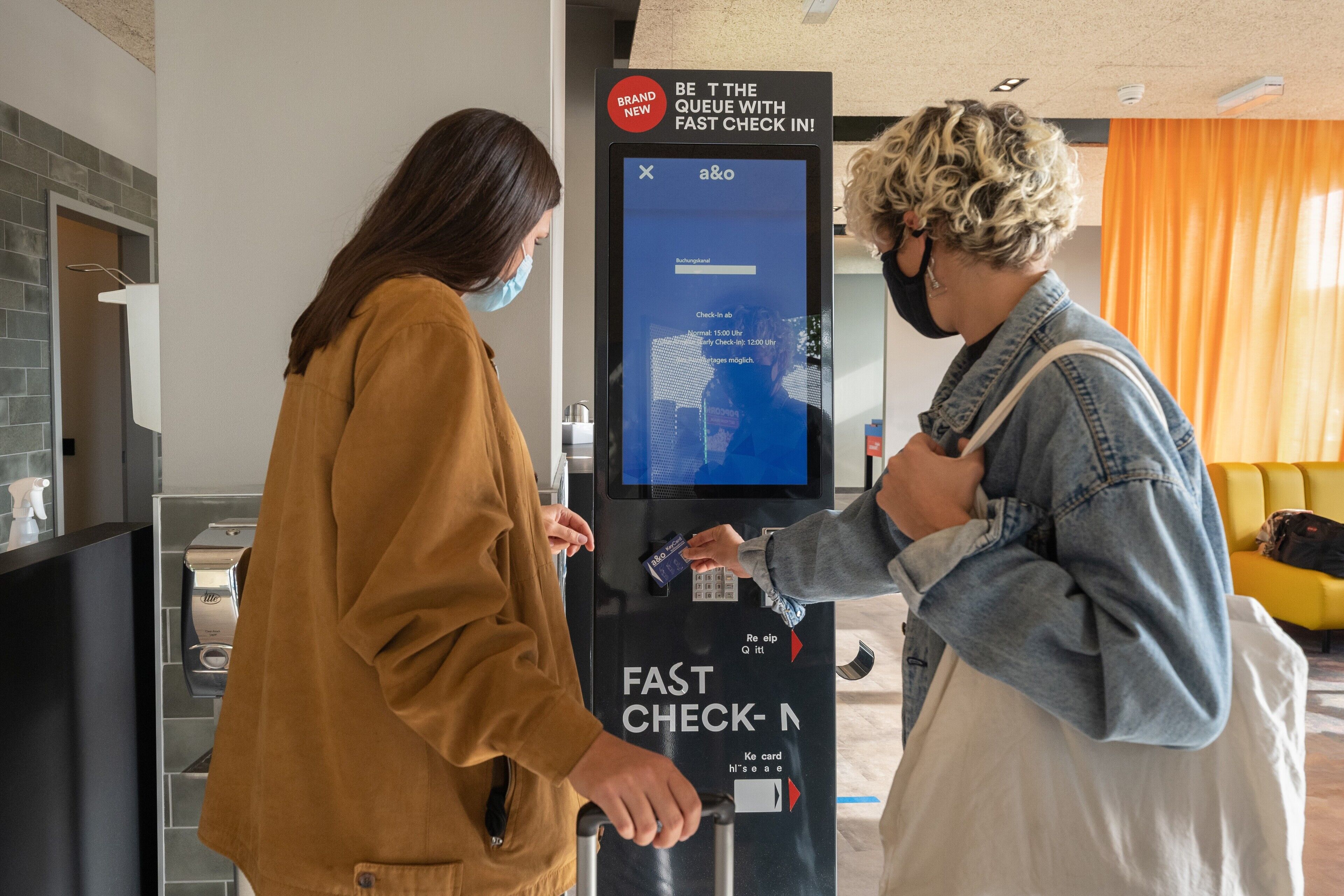 Ein Selbstbedienungs-Check-in-Terminal mit einem digitalen Bildschirm, der eine neue Meldung und einen QR-Code anzeigt.
