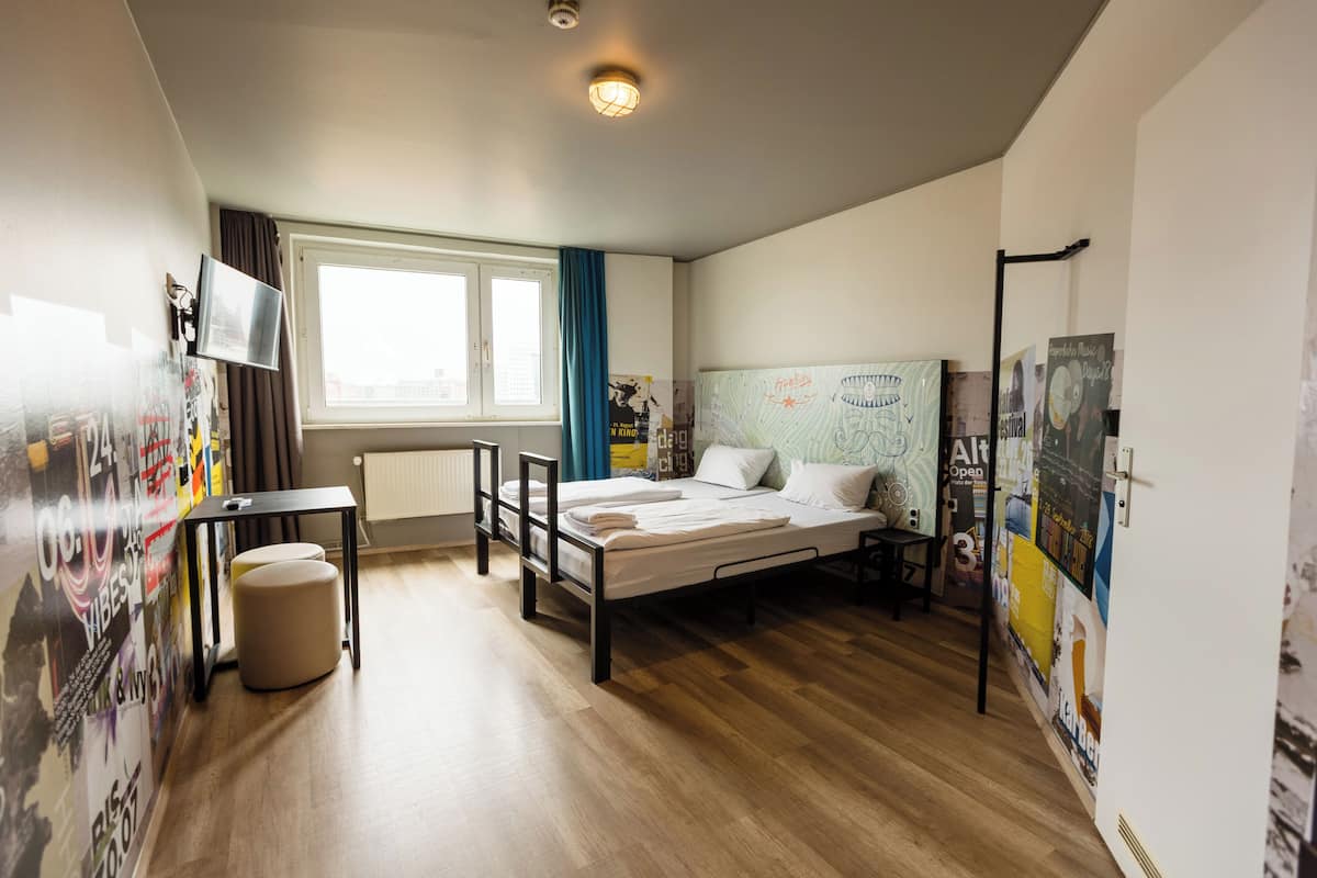 Ein Schlafzimmer mit Bett, Schreibtisch, Stuhl und Fenster.