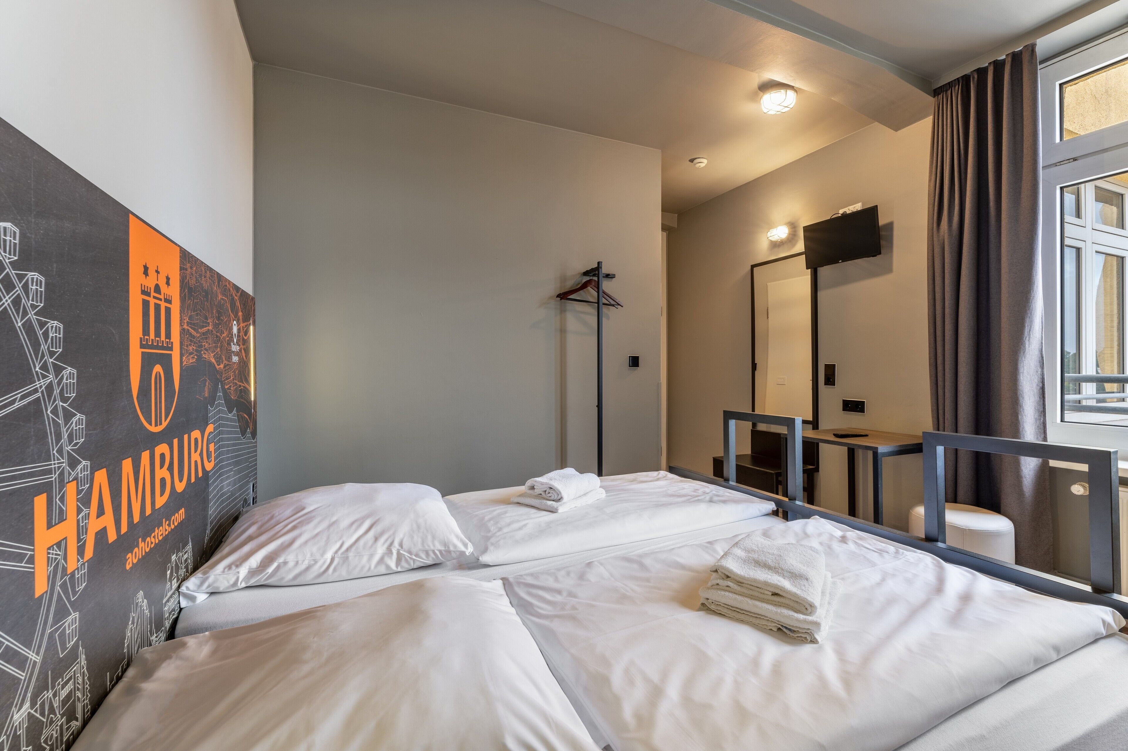 Ein Hotelzimmer mit zwei Betten, einem großen Spiegel, einem Fernseher und einem Bild an der Wand.