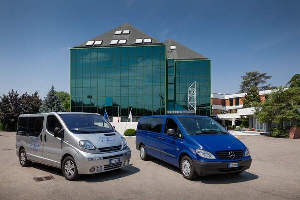 Two vans parked in front of a modern building with a glass facade. - Hotel & Loisir Le Ruote (Cadeo)