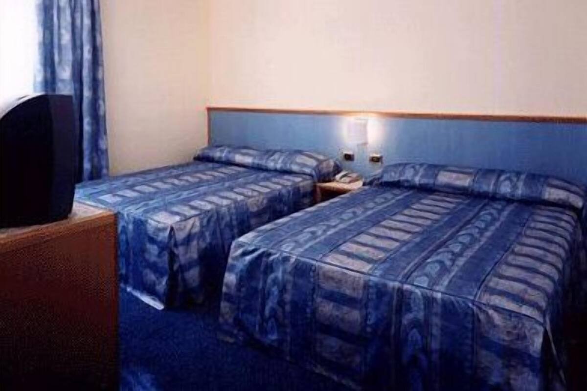 Ein Hotelzimmer mit zwei Betten, einem Fernseher und einem Nachttisch.