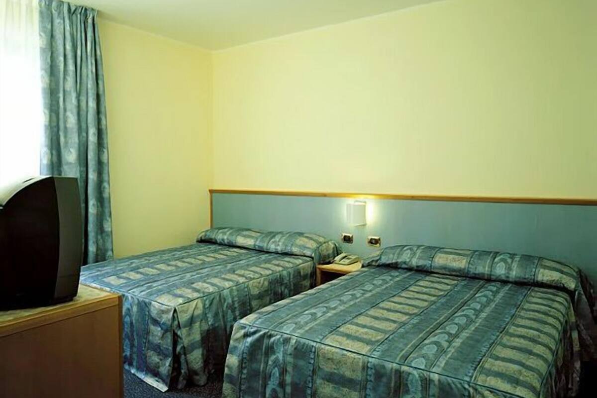 Ein Hotelzimmer mit zwei Betten, einem Fernseher und einem Nachttisch.
