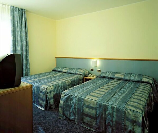 A hotel room with two beds, a television, and a nightstand.
