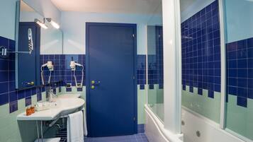 Un baño con puerta azul, un lavabo, un espejo y una bañera.