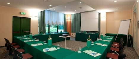 A conference room with a long table, chairs, a projector screen, and a whiteboard.