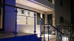 A modern staircase with glass railings and metal handrails, leading to an upper floor. - Poseidon Hotel and Apartments (Kos)
