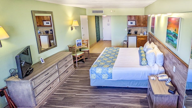 Habitación de hotel con cama, escritorio, cómoda, televisor, microondas y una pequeña kitchenette.
