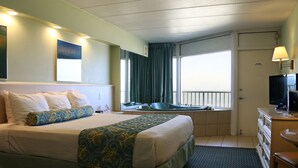 Una habitación de hotel con una cama grande, un escritorio con computadora, un televisor y una ventana con cortinas.