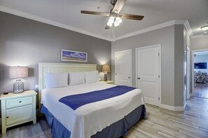 A bedroom with a bed, nightstands, a ceiling fan, and a door.