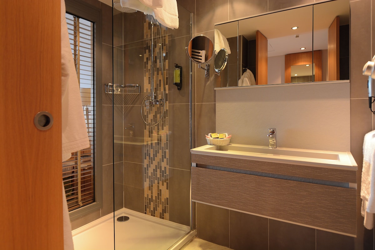 A modern bathroom with a glass shower enclosure, a vanity with a mirror, and a towel rack.