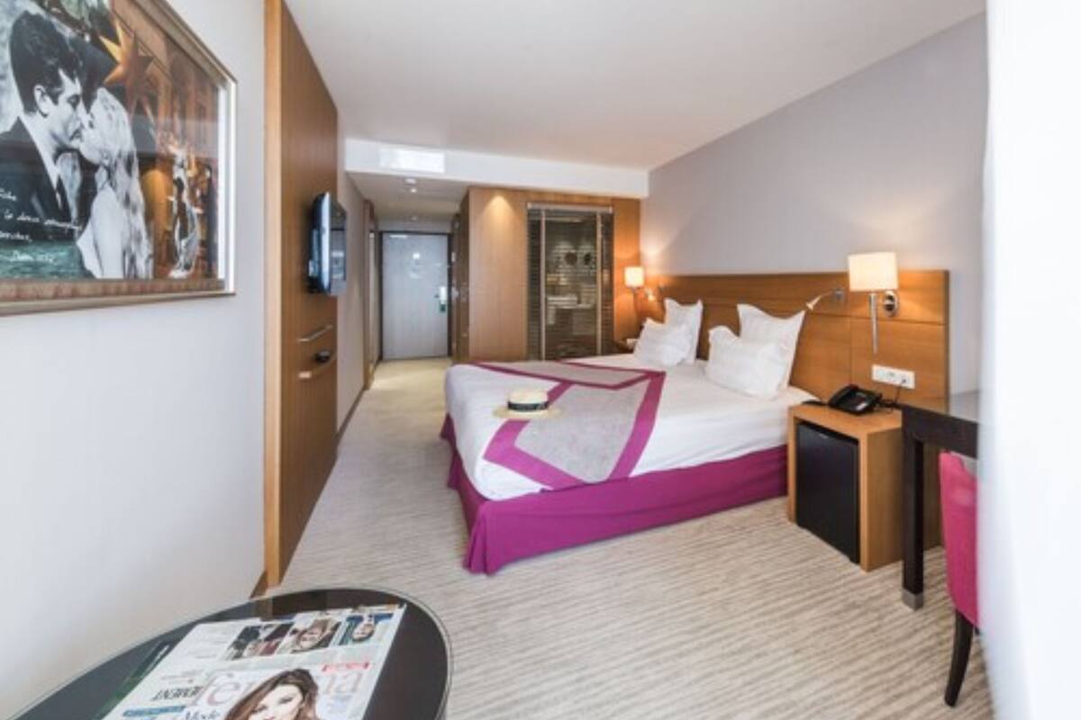Ein Hotelzimmer mit einem Bett, einem Schreibtisch, einem Stuhl, einem Fernseher und einer Zeitschrift auf dem Tisch.