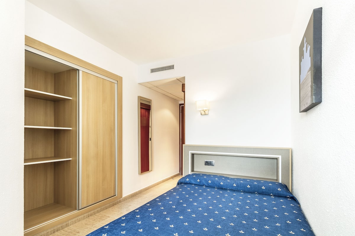 A bedroom with a bed, a wardrobe, and a door leading to another room.
