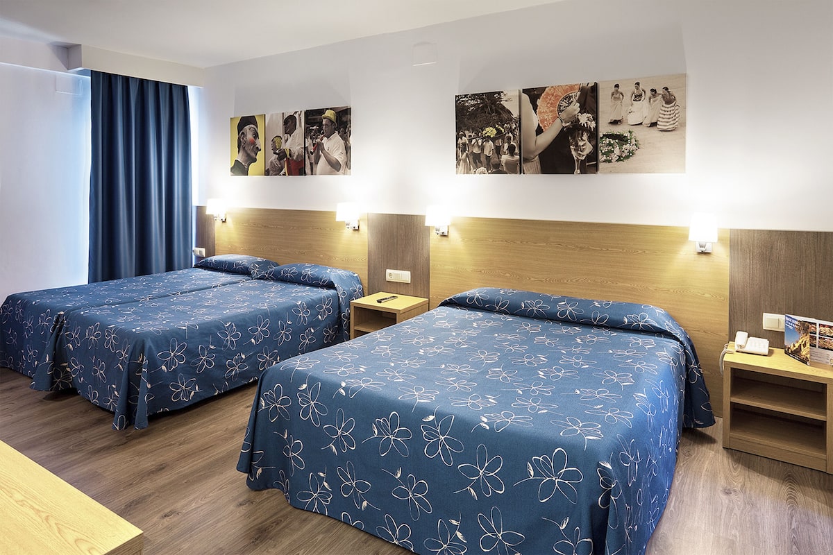 A hotel room with two beds, wooden headboards, and a wall decorated with black and white photographs.