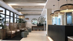 A modern lobby with a reception desk, seating areas, and large windows.