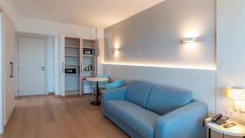 Ein modernes Hotelzimmer mit einer Couch, einem kleinen Tisch, einer Mikrowelle und einem Kleiderschrank.