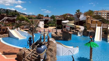 Parque acuático con toboganes, piscina y palmeras.