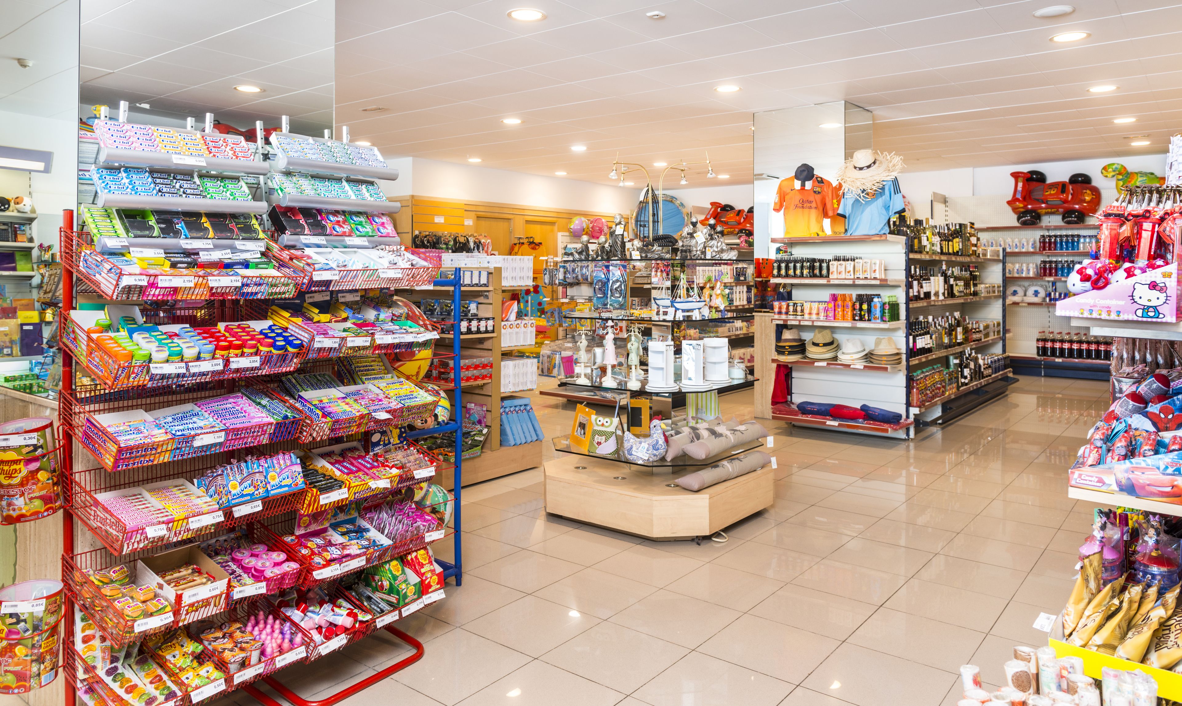 Una tienda bien iluminada con estantes llenos de diversos productos, como aperitivos, bebidas y artículos del hogar.
