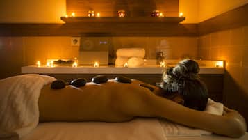 Experience a tranquil spa setting with a soothing massage, a large mirror, and candles creating a peaceful ambiance.