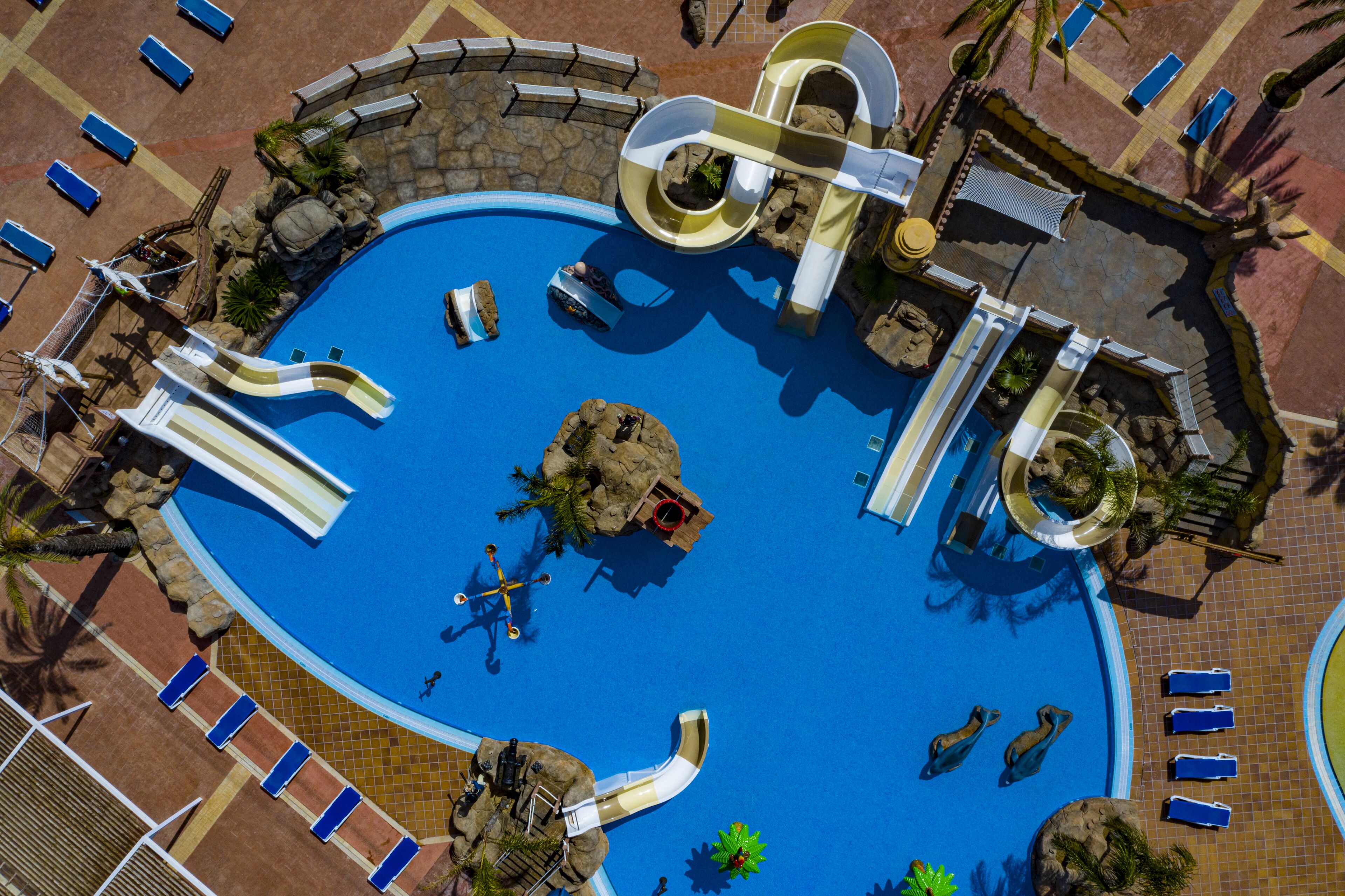 Uma piscina grande com vários toboáguas e uma ilha central.