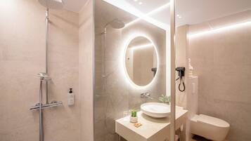Un baño moderno con ducha de vidrio, un espejo redondo, un lavabo y un inodoro.