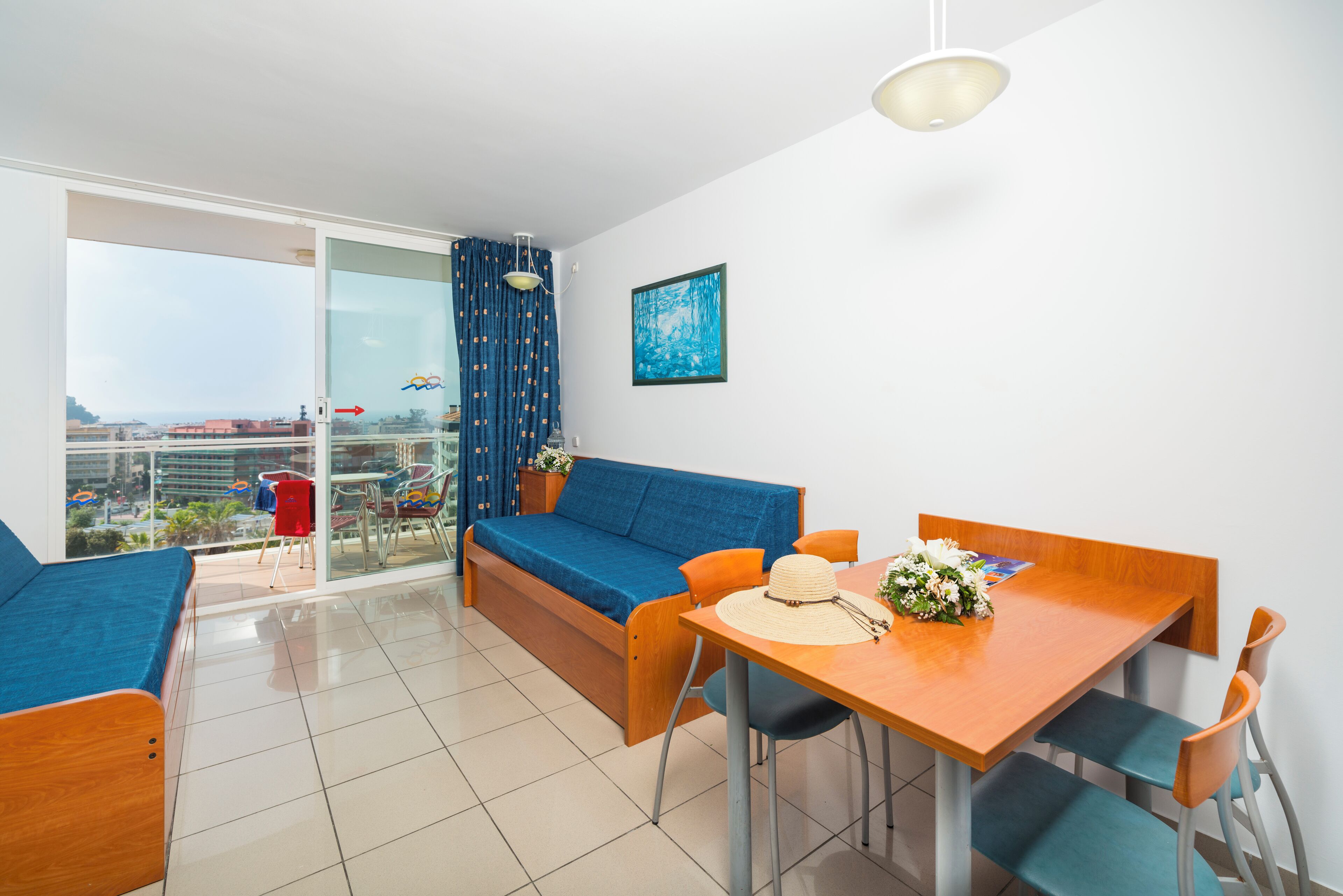 A modern room with a sofa, dining table, chairs, and a view through a glass door.